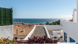 A rooftop terrace with a view of the sea, white buildings, and a green hedge. - Apartment 'Duquesa Suites Golf and Gardens' with Shared Pool, Wi-Fi and Air Conditioning (Manilva)