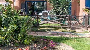 A gated patio area with a pool table, lounge chairs, and a view of the pool. - Apartment 'Duquesa Suites Golf and Gardens' with Shared Pool, Wi-Fi and Air Conditioning (Manilva)