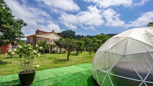 Une maison avec un jardin, une serre et une structure en forme de dôme.