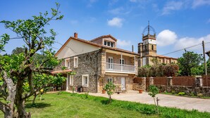 Une maison en pierre avec un balcon, une tour et un ciel dégagé.