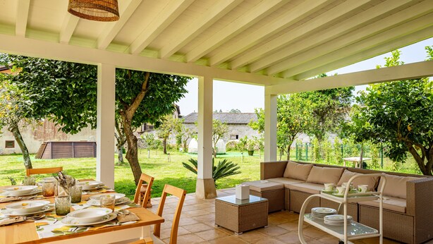 Une terrasse extérieure aménagée avec une table à manger, un canapé et un chariot contenant des assiettes.