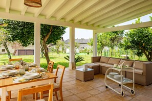 Un patio al aire libre con una mesa de comedor, un sofá y un carrito con platos.