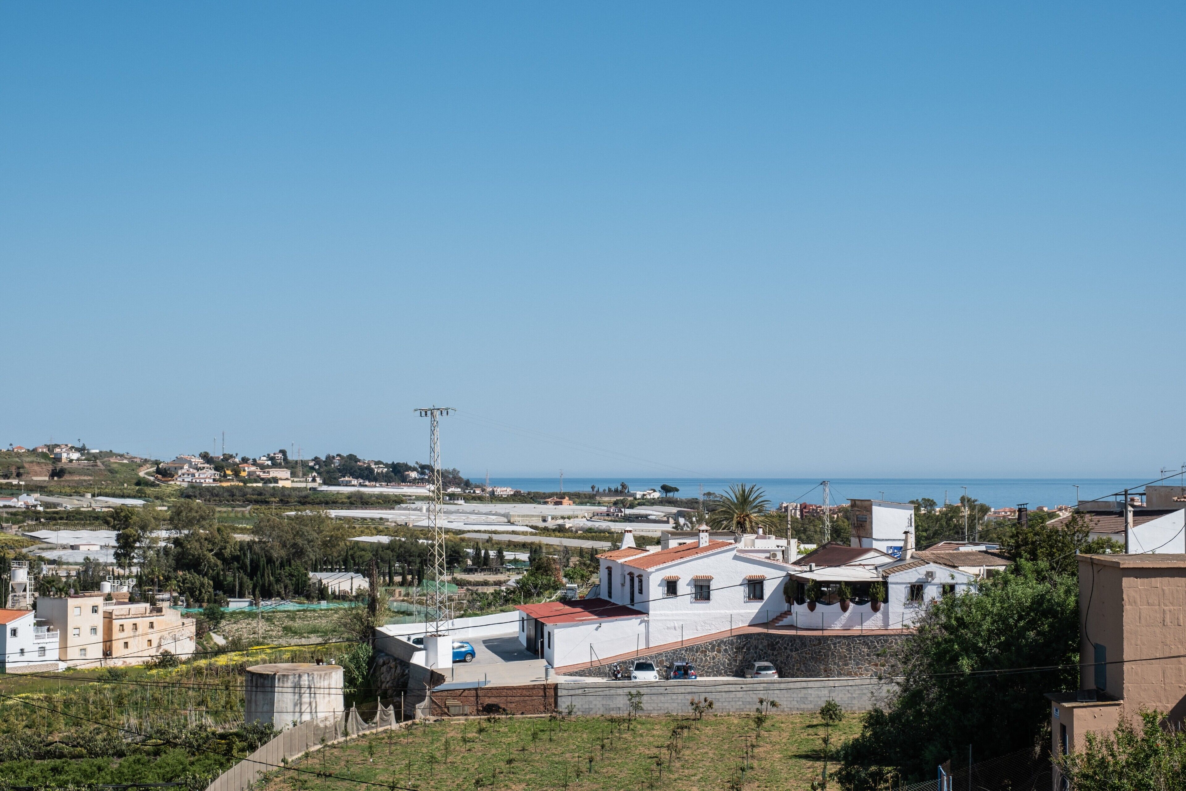 Eine Wohngegend an der Küste mit Häusern, blauem Himmel und Blick auf das Meer.