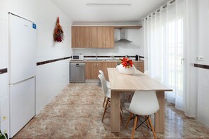 Eine moderne Küche mit weißen Schränken, einem Holzespeisetisch und einem weißen Kühlschrank.