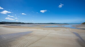 A beach with sand and water, a clear sky, and distant hills. - Holiday Home 'Gite Des Hauts Grève - Near the Sea' with Terrace, Garden & Wi-Fi (Saint-Michel-en-Grève)