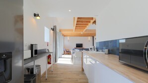 A modern kitchen with a wooden ceiling, a built-in oven, and a large island with a microwave. - Holiday Home 'Gite Des Hauts Grève - Near the Sea' with Terrace, Garden & Wi-Fi (Saint-Michel-en-Grève)