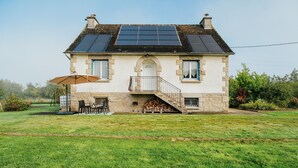 A two-story house with a stone facade, a front door, a staircase, and solar panels on the roof.
