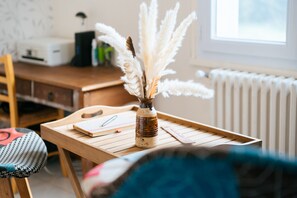 Une table en bois sur laquelle se trouvent un vase rempli de plumes blanches, un carnet et un stylo.