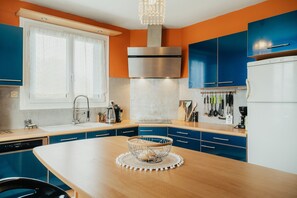 Une cuisine moderne avec des meubles bleus, une hotte en acier inoxydable et un îlot central doté d’un évier.