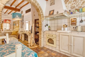 A rustic kitchen with exposed brick walls, a wooden ceiling, and a tiled backsplash.