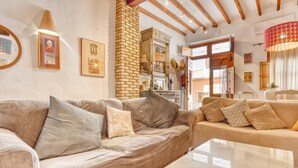 A modern living room with a beige sofa, a glass coffee table, and a brick fireplace. - Designer Country House Near the Sea (La Nucia)