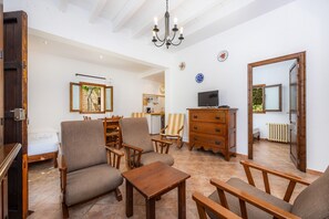 A spacious living area with a large wooden dining table, several chairs, a television, and a mirror.
