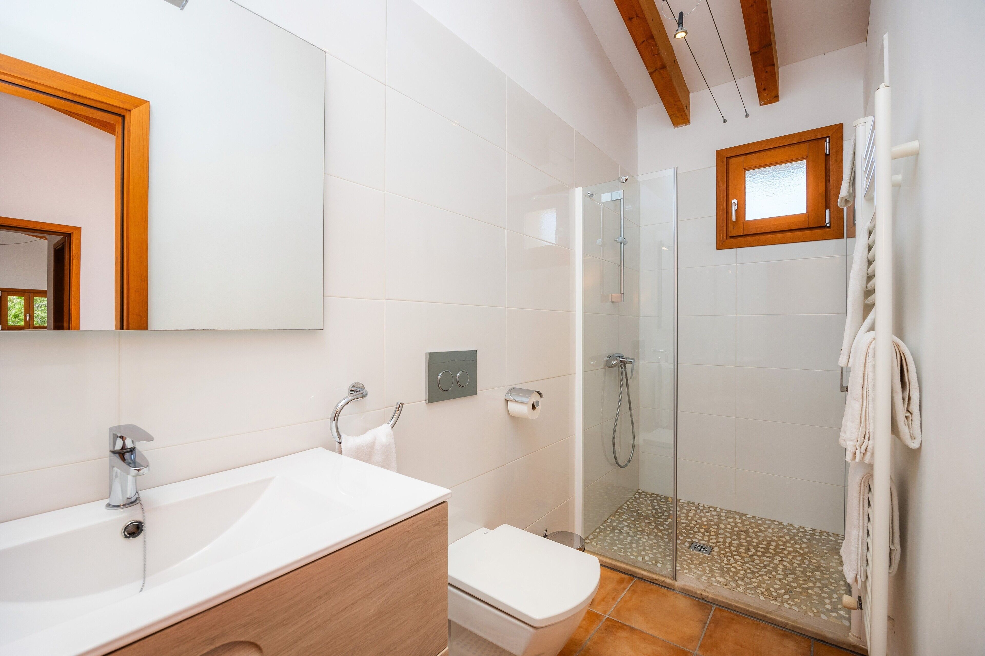 Une salle de bain moderne avec une douche à parois de verre, un lavabo blanc et un meuble-lavabo en bois.