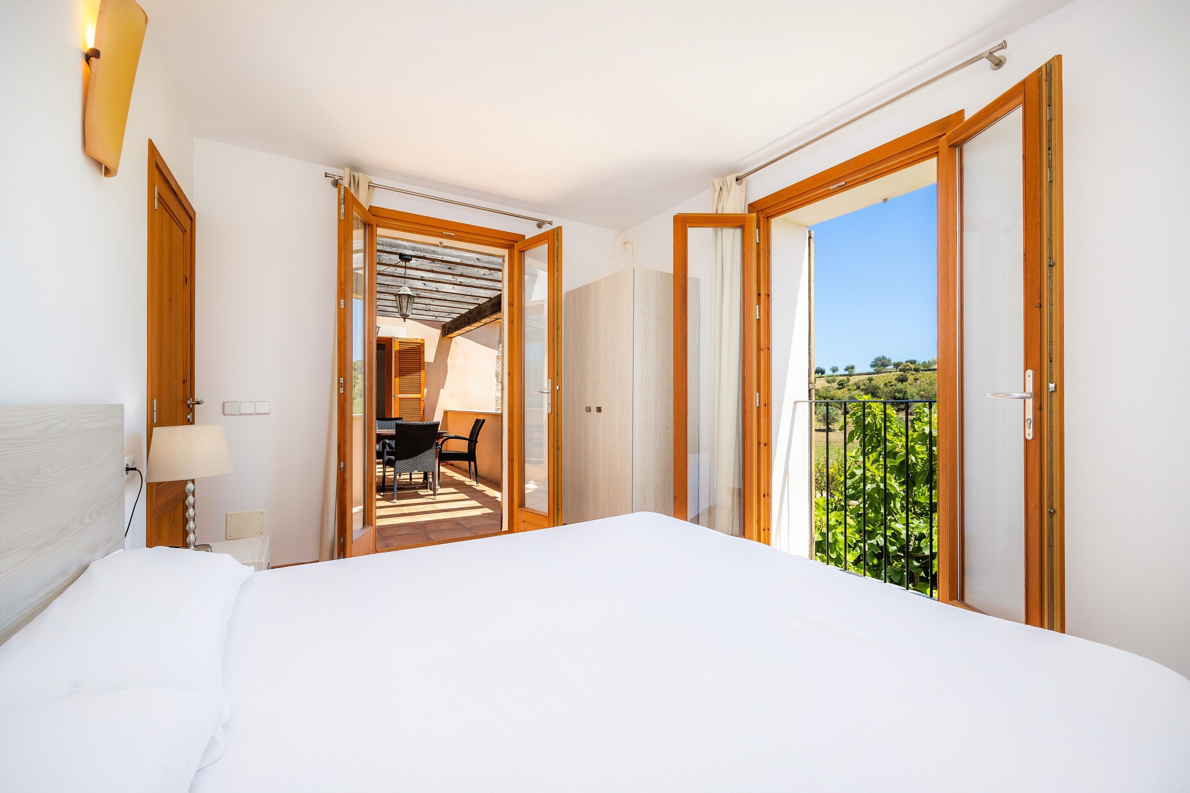 Hotelkamer met een bed, een bureau en uitzicht op groen via een schuifdeur.