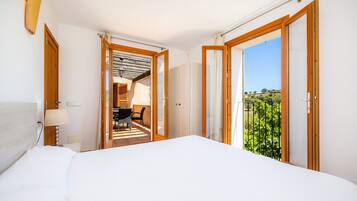 Hotelkamer met een bed, een bureau en uitzicht op groen via een schuifdeur.