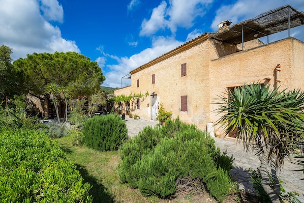 A stone building with a courtyard, surrounded by greenery.
