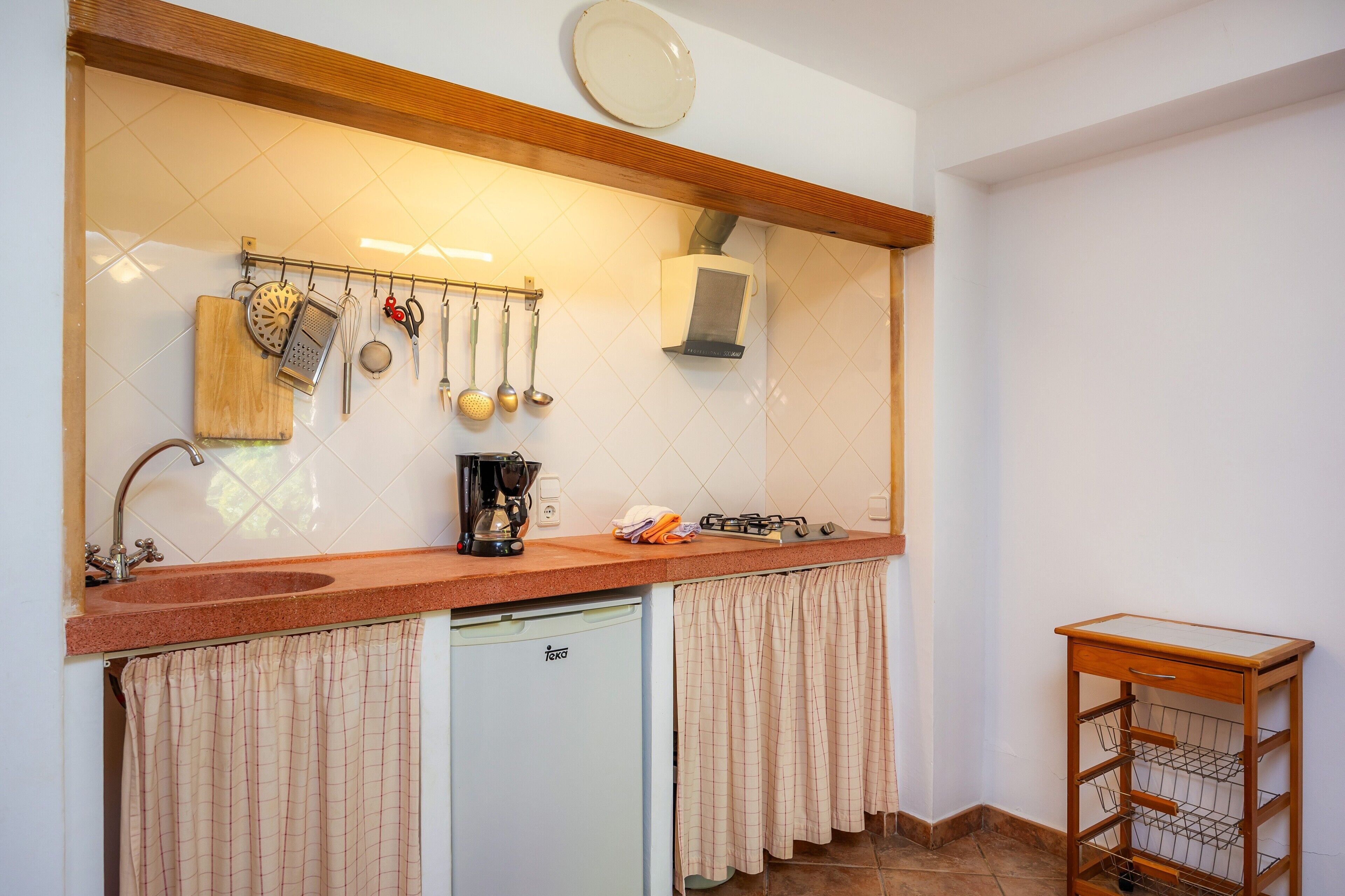 Una cocina con un fregadero, una cafetera y un escurreplatos.