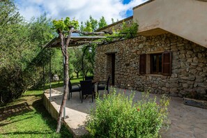Un bâtiment en pierre doté d’une pergola, d’un espace extérieur aménagé pour s’asseoir et d’un jardin.