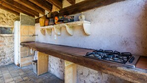 A rustic kitchen with a wooden countertop, a gas stove, and shelves with various kitchen items. - Apartment 'Sa Soll' with Mountain Views, Shared Pool and Wi-Fi (Illes Balears)