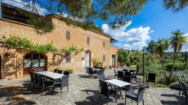 A stone building with outdoor seating and greenery. - Apartment 'Es Sostre' with Mountain Views, Shared Pool and Wi-Fi (Illes Balears)