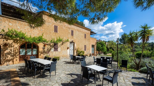 A stone building with outdoor seating and greenery. - Apartment 'Sotil De Ponent' with Mountain Views, Shared Pool and Wi-Fi (Illes Balears)