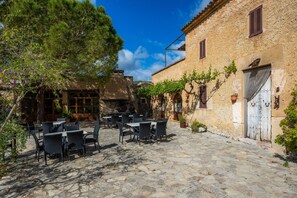 A cobblestone courtyard with outdoor seating, stone walls, and a rustic building.