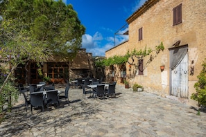 A cobblestone courtyard with outdoor seating, stone walls, and a rustic building.
