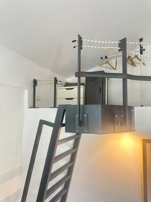 A bunk bed with a ladder and a pull-up bar. There is a white wall and a door in the background.