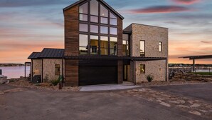A modern two-story house with a garage, large windows, and a stone facade.
