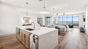 A spacious kitchen with a large island, modern pendant lighting, and a view of the outdoors.