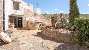 Un edificio de piedra con una puerta, una chimenea y un árbol grande al frente.
