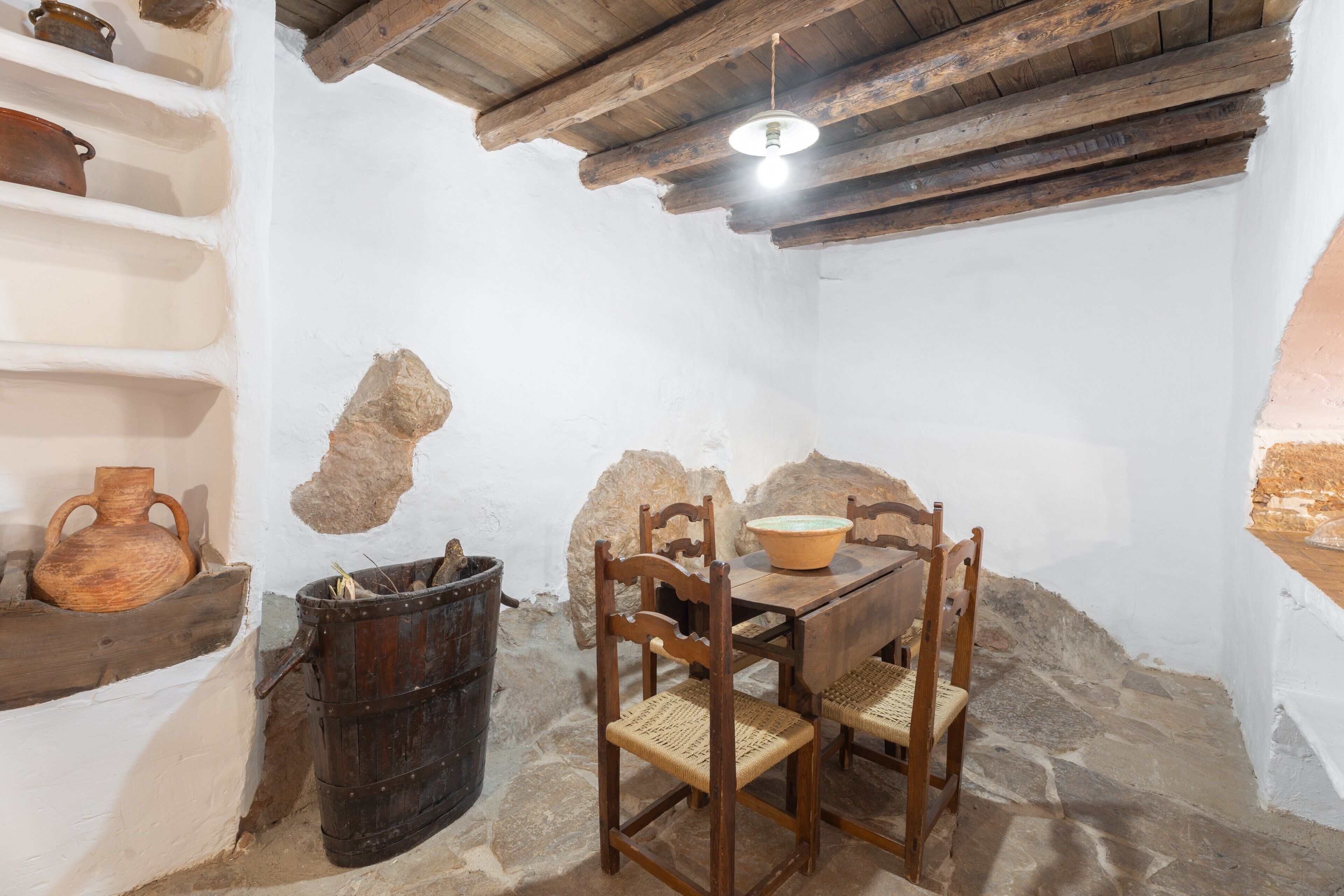 Una habitación rústica con suelo de piedra, muebles de madera y una lámpara colgante.