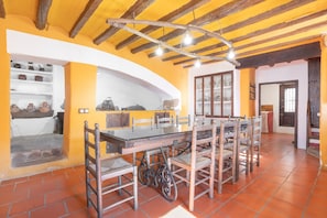 A dining area with a long table, chairs, and a rustic ceiling.