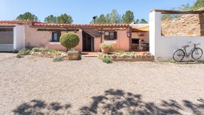 A rustic building with a gravel driveway, a bicycle, and a stone wall. - Apartment 'Cau' with Mountain Views, Shared Pool and Private Terrace (La Torre D'en Besora)