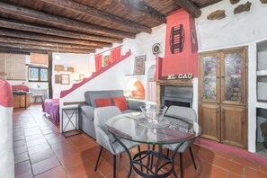Un interior acogedor con una escalera, un sofá, una mesa de vidrio y una chimenea.