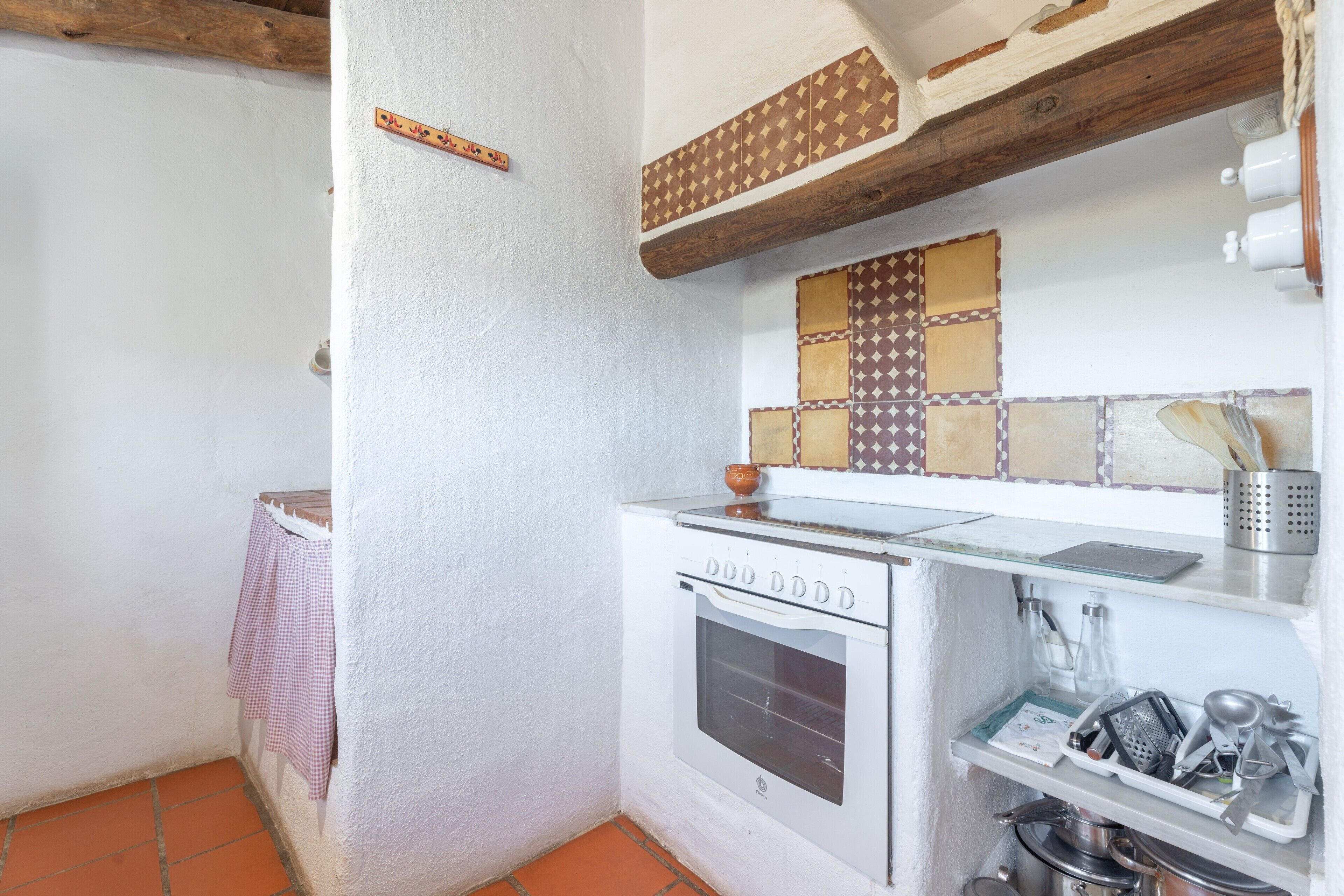 A kitchen with a white oven, a tiled backsplash, and a hanging pot rack.