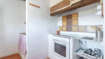 A kitchen with a white oven, a tiled backsplash, and a hanging pot rack.