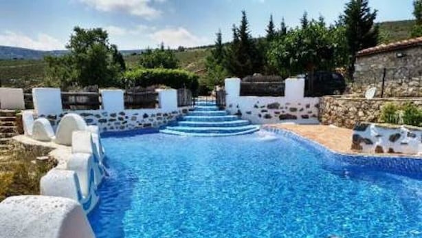 Piscina com degraus para acesso, rodeada por paredes brancas e detalhes em pedra.