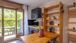 Une cuisine avec une table en bois, un four à micro-ondes et un placard.