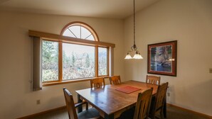 Ein Esszimmer mit Holztisch und -stühlen, einem großen Bogenfenster und einem Bild an der Wand.