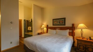 Ein Hotelzimmer mit einem großen Bett, zwei Nachttischlampen, einem hölzernen Kopfteil und einem gerahmten Bild an der Wand.