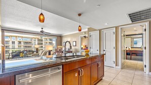 A modern kitchen with a stainless steel dishwasher, wooden cabinets, and pendant lighting.
