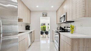 Una cocina moderna con electrodomésticos de acero inoxidable, armarios de madera y encimera blanca.