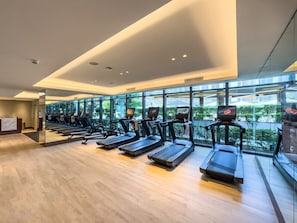 A modern gym with multiple treadmills aligned in rows, large windows offering views of the outdoors, and a clean, minimalist design. - NEW | 3BR Burj Fountain NYE View | Address (Dubai)