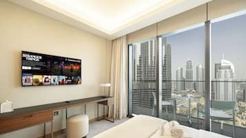 Ein modernes Hotelzimmer mit einem großen Bett, einem Schreibtisch, einem Stuhl und einem Fernseher, der Filmplakate zeigt.