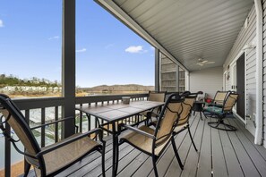A covered outdoor patio with a table and chairs, overlooking a body of water and distant hills. - Norris Lake Deerfield Resort golf, winery, community pools, tennis, boating (LaFollette)
