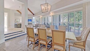 A spacious dining area with a long table, several chairs, and a hanging light fixture. - Fabulous Location! Sleeps 12! Walk to Club/Beach! Amenity access included (Seabrook Island)