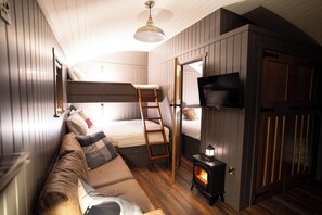 A cozy room with a bunk bed, a sofa, a television, and a wood-burning stove. - Charming Lodge in Limavady, Sleeps 5 with Parking (Limavady)