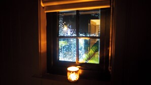 Una ventana con vistas a un edificio y una vela en el alféizar.
