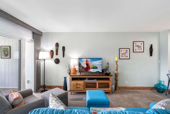 Un salon avec un téléviseur, un meuble de rangement en bois et un canapé.